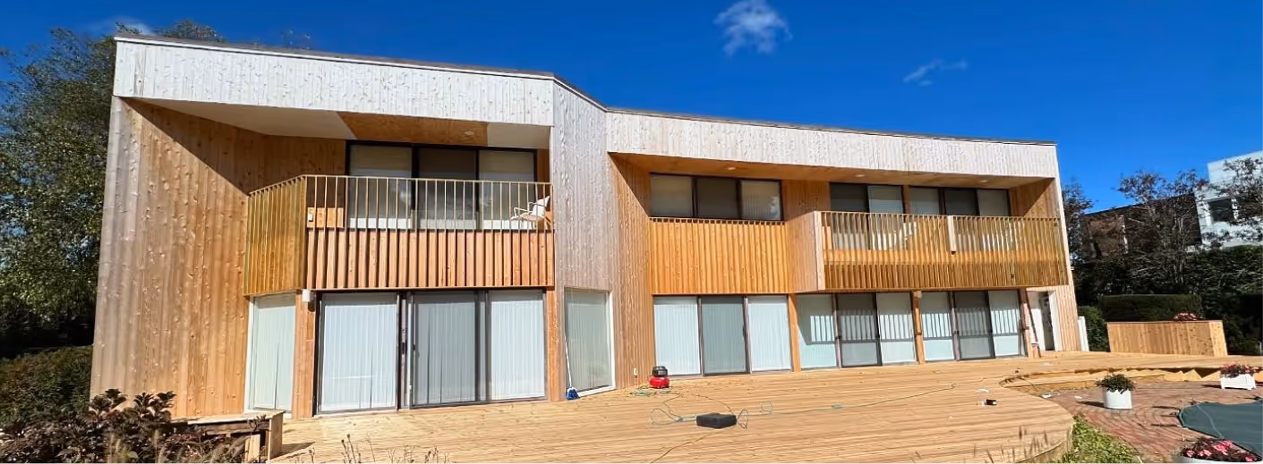 Modern wood-clad house freshly painted by Palencia’s Painting & Window Cleaning, showcasing smooth finishes and natural tones under a clear Long Island sky