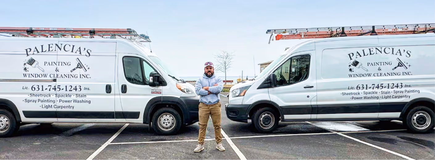 Eber Palencia standing between company vans of Palencia’s Painting & Window Cleaning Inc. in Long Island, ready for residential and commercial painting and cleaning services