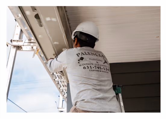 Professional painter from Palencia’s Painting & Window Cleaning working on exterior soffit and trim of a Long Island home